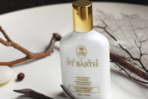 detail shot of a bottle of body lotion. The white cream shows through the see through bottle and has a gold cap and gold writing on the label.