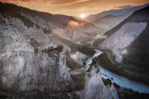 post card view of the sun setting over a valley of mountains