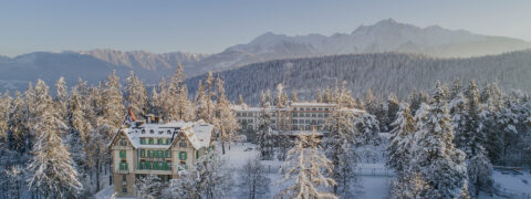 overview of the resort surrounded by trees and mountains all covered with snow, blue sky with morning sunrise glow