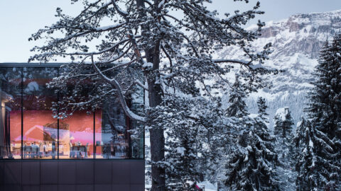 Beautiful Epoca restaurant exterior surrounded by snow cover trees and mountains under a blue sky